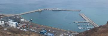 Aerial view of the harbour of Porto Santo Island with a ferry in the waters and the coastline of Madeira in the distance.